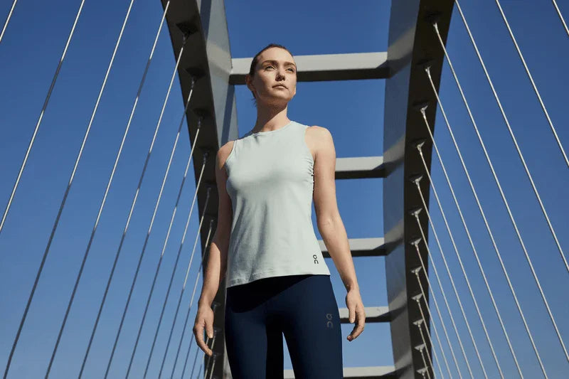Woman in athletic wear standing on a bridge with a clear blue sky