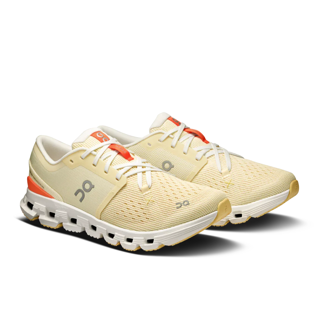 Angled Lateral side view a pair of Women's light yellow On Cloud X 4 with white sole and laces, and orange accents