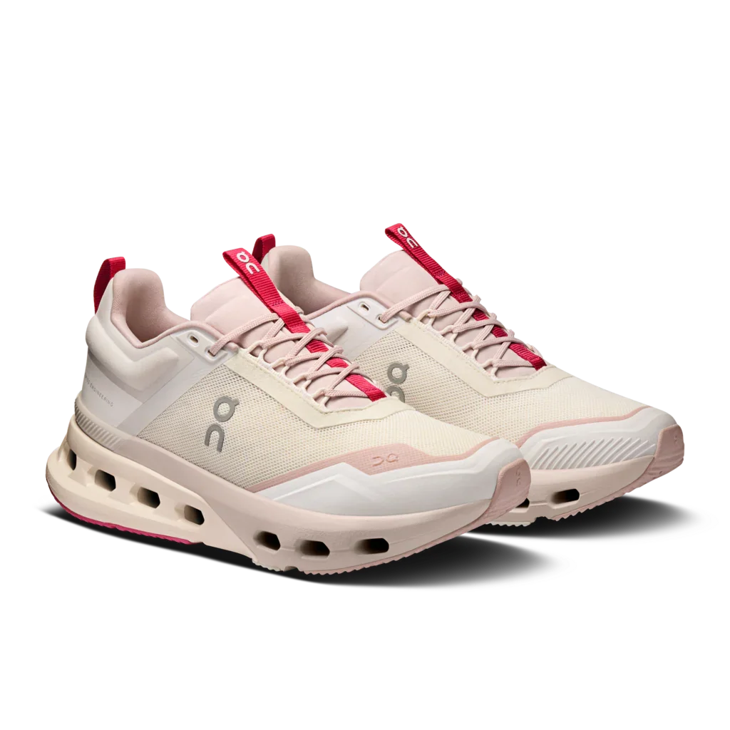 Angled side view of a pair of Women's light pink and white On Cloudnova X training shoes with dark pink detailing