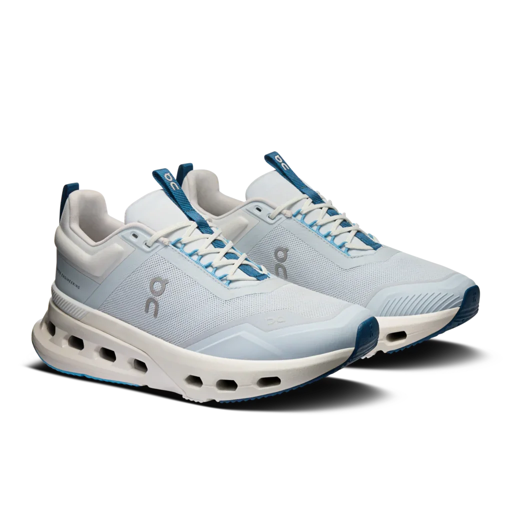 Angled side view of a pair of Women's Light blue and white On Cloudnova X training shoes with dark blue detailing